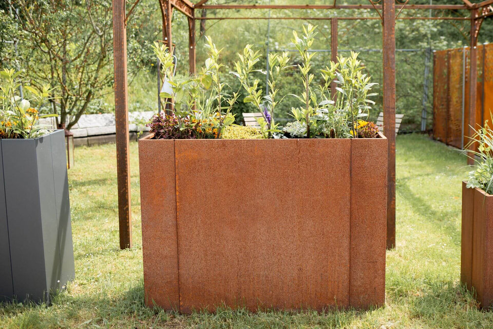 Hochbeet Manarola in einem sommerlichen Garten mit ELEO Pavillon und Sichtschutzelementen im Hintergrund | Cortenstahl Hochbeet Manarola in einem sommerlichen Garten mit ELEO Pavillon und Sichtschutzelementen im Hintergrund | Cortenstahl