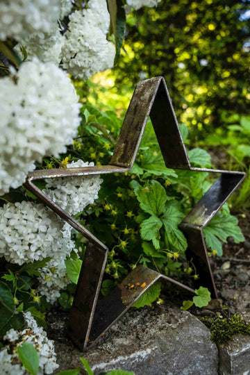 Metallstern Novara klein auf Steinen vor weißen Blüten, unbeschichtet